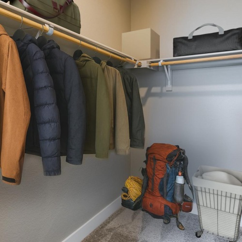 a closet with clothes and a backpack